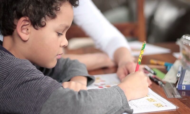 dete radi domaći uz pomoć starije osobe